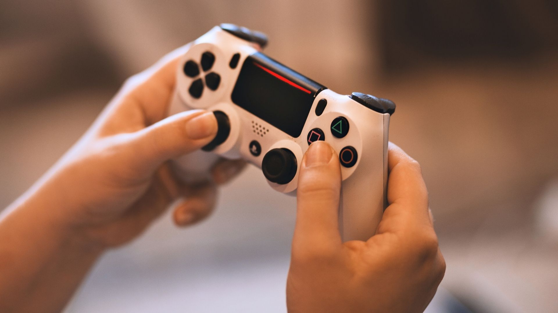 Person hält einen Gamecontroller in den Händen: Sinnbild für die Games-Branche