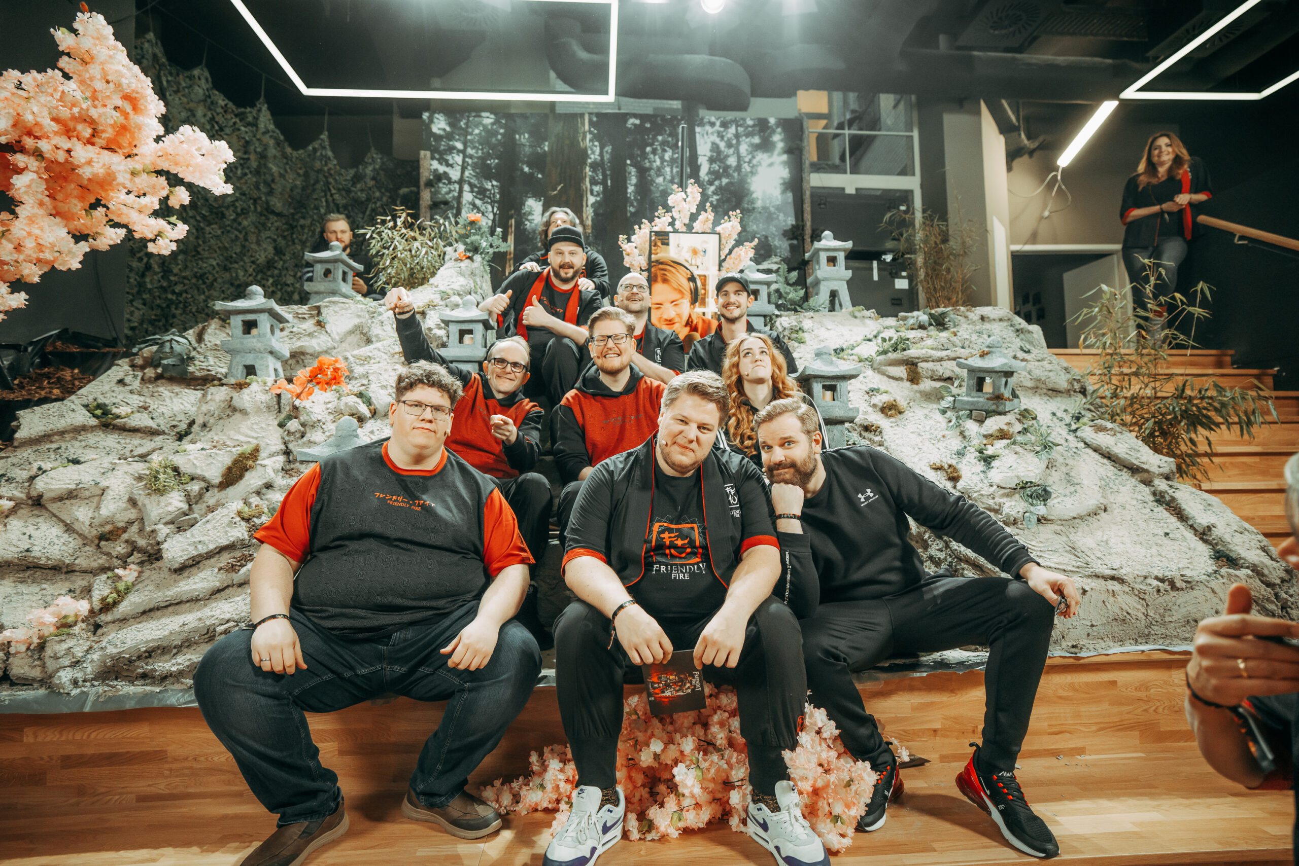 Die Gastgebenden des Friendly Fire 10 sitzen auf den Stufen der Eventarena des R42