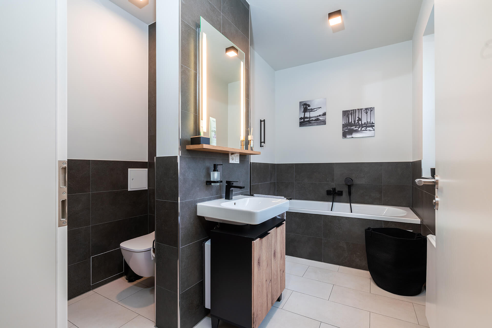 Modern eingerichtetes Apartment namens Lara's Loft im R42 in Leipzig, graues Badezimmer mit Badewanne und begehbarer Dusche, Toilette und Waschbecken.