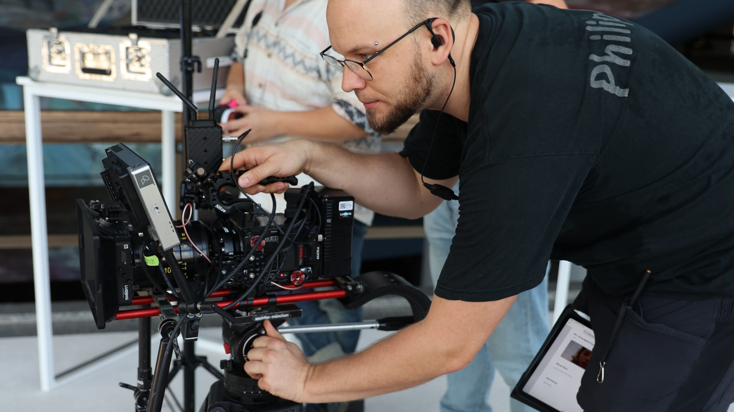 Ein Kameramann steht nach vorn gebeugt an einer Kamera.